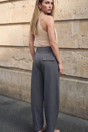Pantalón de fit balloon, pinzas frontales, cintura alta con pretina y trabillas, bolsillos delanteros y posterior con cartera. Cierre frontal con broche y cremallera ocultos.