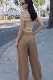 Pantalón de fit balloon, pinzas frontales, cintura alta con pretina cruzada y trabillas, bolsillos delanteros, vivo decorativo posterior, cierre frontal con botón y cremallera oculta.