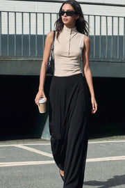 Pantalón de fit wide leg, pinzas frontales, cintura alta con pretina y cruce frontal decorativo. Cierre lateral con cremallera oculta.