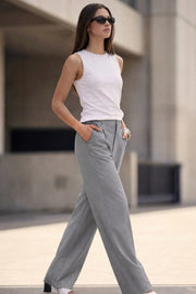 Pantalón de fit recto, cintura alta con pretina y trabillas, bolsillos delanteros y vivos decorativos posteriores, pinzas frontales. Cierre con botón y cremallera oculta.