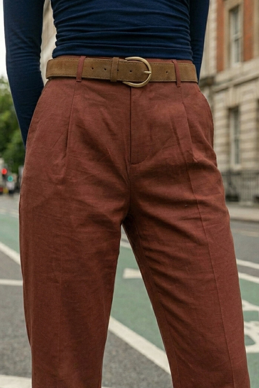 Pantalón de fit recto, cintura alta con pretina y trabillas, bolsillos delanteros y vivos decorativos posteriores. Detalle de raya frontal y posterior, cinturón con hebilla en contraste, cierre frontal con broche y cremallera ocultos.