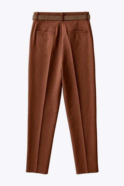 Pantalón de fit recto, cintura alta con pretina y trabillas, bolsillos delanteros y vivos decorativos posteriores. Detalle de raya frontal y posterior, cinturón con hebilla en contraste, cierre frontal con broche y cremallera ocultos.