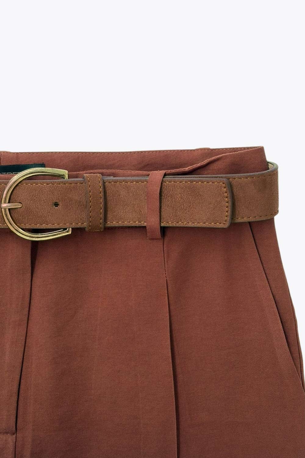 Pantalón de fit recto, cintura alta con pretina y trabillas, bolsillos delanteros y vivos decorativos posteriores. Detalle de raya frontal y posterior, cinturón con hebilla en contraste, cierre frontal con broche y cremallera ocultos.