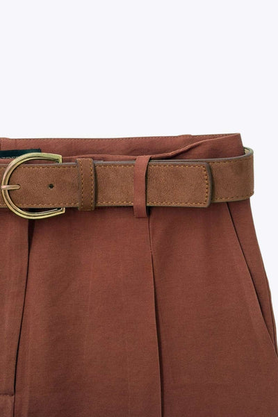 Pantalón de fit recto, cintura alta con pretina y trabillas, bolsillos delanteros y vivos decorativos posteriores. Detalle de raya frontal y posterior, cinturón con hebilla en contraste, cierre frontal con broche y cremallera ocultos.