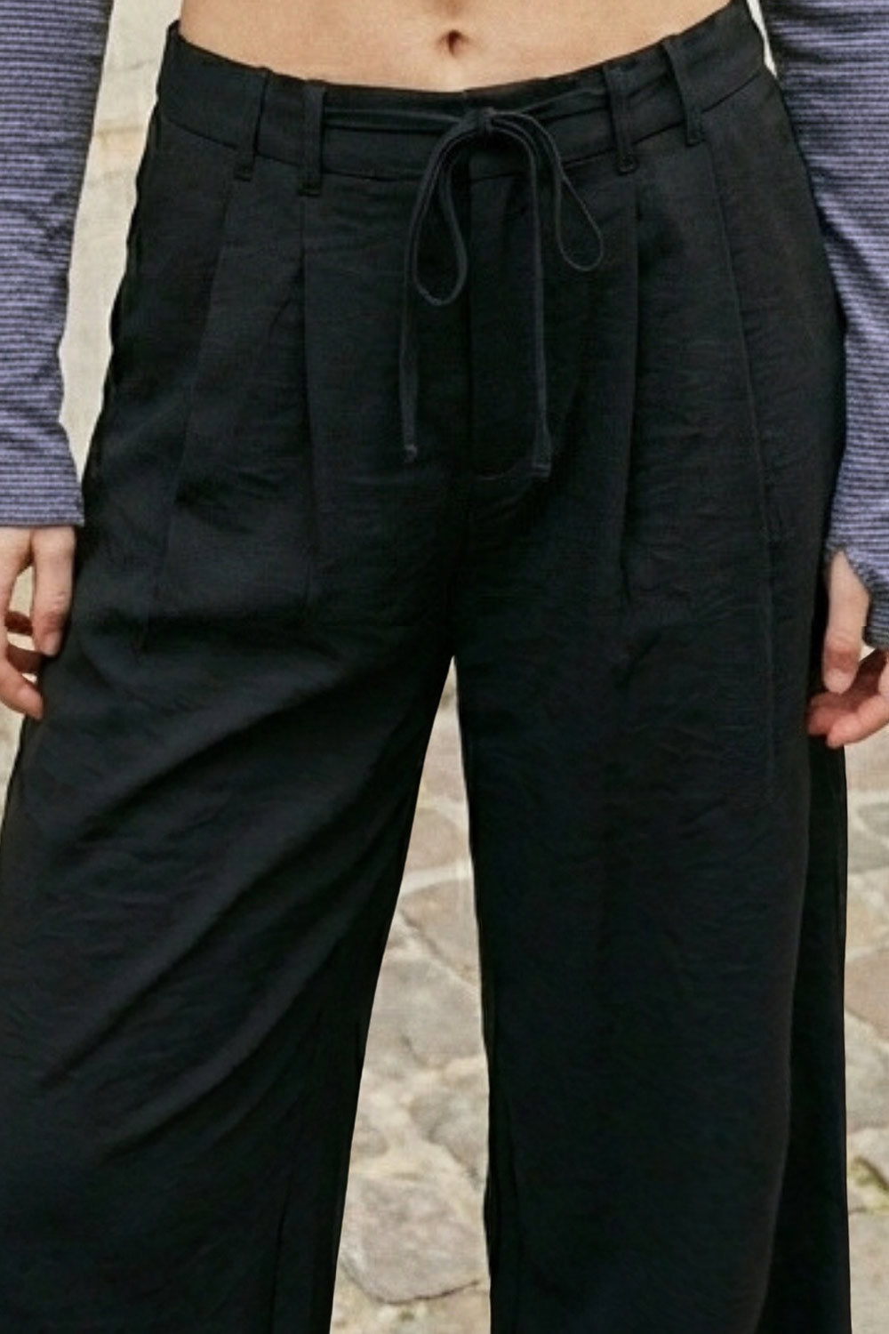 Pantalón de fit recto, pinzas frontales, cintura alta con pretina y trabillas, bolsillos delanteros, vivo decorativo posterior, cierre frontal con broche y cremallera ocultos. Detalle de jareta frontal ajustable en cintura.