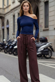 Pantalón de fit recto, pinzas frontales, cintura alta con pretina y trabillas, bolsillos delanteros, vivo decorativo posterior, cierre frontal con broche y cremallera ocultos. Detalle de jareta frontal ajustable en cintura.