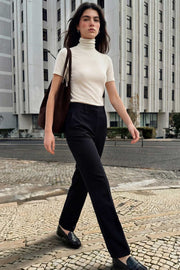 Pantalón básico de fit recto, cintura alta con pretina elástica posterior, raya frontal y posterior, cierre con broche y cremallera ocultos.