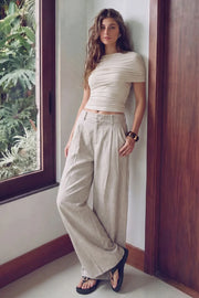 Pantalón de fit wide leg, cintura alta con pretina y trabillas, pinzas frontales, bolsillos delanteros, vivos decorativos posteriores, cierre frontal con broche y cremallera ocultos. Detalle de trabillas laterales ajustables en cintura con botones en contraste.