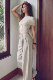 Pantalón de fit wide leg, cintura alta con pretina y trabillas, pinzas frontales, bolsillos delanteros, vivos decorativos posteriores, cierre frontal con broche y cremallera ocultos. Detalle de trabillas laterales ajustables en cintura con botones en contraste.
