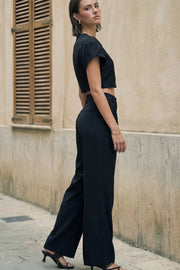 Pantalón de fit wide leg, cintura alta con pretina con detalle v posterior y trabillas, pinzas frontales, bolsillos delanteros, vivos decorativos posteriores, cierre frontal con botón en contraste y cremallera oculta.