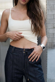 Pantalón de denim, fit wide leg, bolsillos delanteros y traseros de parche, cintura alta con pretina elástica posterior, trabillas y cinturón amarrable del mismo tejido. Detalle de raya decorativa frontal.