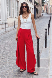 Pantalón fluido de fit wide leg, cintura alta con pretina, pinzas frontales con detalle decorativo, bajo curveado asimétrico con olanes y detalle de abertura laterales. Cierre lateral con cremallera oculta.