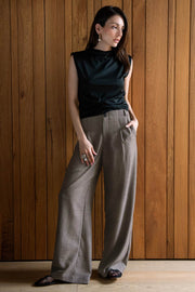 Pantalón fluido de cintura alta con trabillas, fit wide leg, pinzas frontales, bolsillos delanteros y vivos posteriores. Cierre frontal con botón y cremallera oculta.