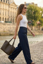 Pantalón fluido de fit wide leg, cintura alta con pretina y trabillas, bolsillos decorativos delanteros y traseros con cartera, costuras frontales decorativas, cierre frontal con botón y cremallera oculta.