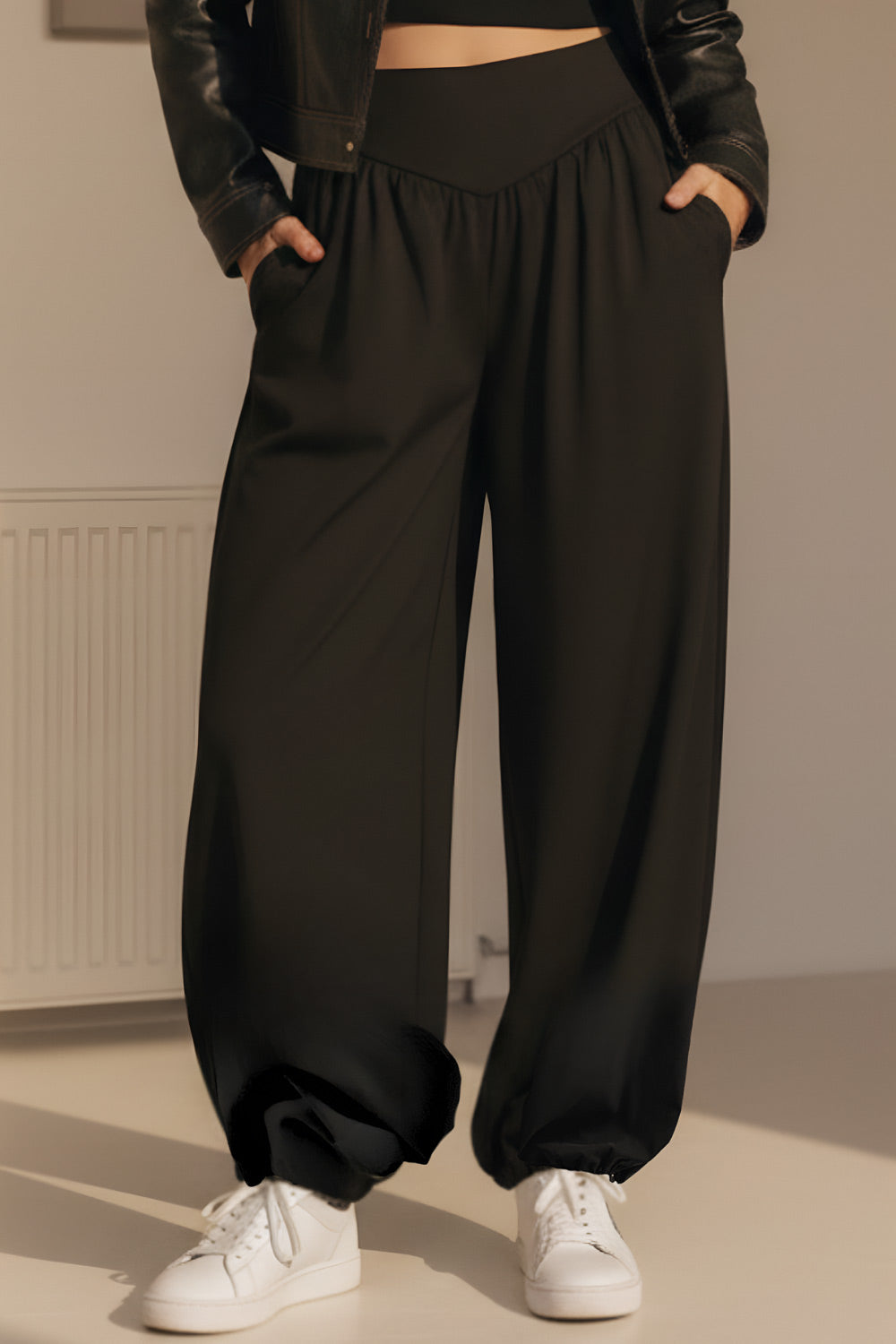 Pantalón de fit harem, cintura alta, peto con corte v frontal y plisado decorativos, rib elástico en bajo y cierre lateral con cremallera oculta.