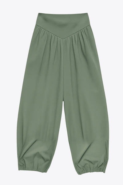 Pantalón de fit harem, cintura alta, peto con corte v frontal y plisado decorativos, rib elástico en bajo y cierre lateral con cremallera oculta.