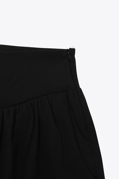 Pantalón de fit harem, cintura alta, peto con corte v frontal y plisado decorativos, rib elástico en bajo y cierre lateral con cremallera oculta.