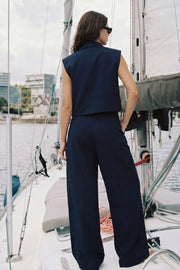 Pantalón de fit wide leg, cintura alta con pretina, trabillas, pinzas frontales y bolsillos delanteros. Cierre frontal con broche y cremallera ocultos.