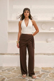 Pantalón fluido de fit recto, cintura media con pretina elástica, bolsillos delanteros y detalle de pareo decorativo con nudo lateral.