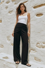 Pantalón fluido de fit recto, cintura media con pretina elástica, bolsillos delanteros y detalle de pareo decorativo con nudo lateral.