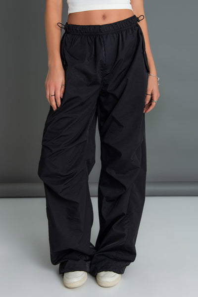 Pantalón parachute de cintura media elástica con doble jareta elástica, fit amplio, plisados frontales y bolsillos frontales decorativos con cartera.