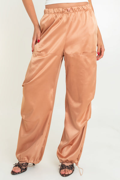 Pantalón parachute satinado de cintura alta con pretina elástica y jareta ajustable, de pierna amplia, plisados decorativos frontales, detalle de bajo con jaretas elásticas ajustables.