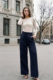 Pantalón de fit wide leg, cintura alta con pretina, trabillas y doble lazo amarrable, pinzas frontales y bolsillos delanteros. Cierre frontal con broche y cremallera ocultos.