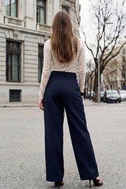 Pantalón de fit wide leg, cintura alta con pretina, trabillas y doble lazo amarrable, pinzas frontales y bolsillos delanteros. Cierre frontal con broche y cremallera ocultos.