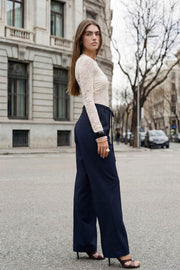Pantalón de fit wide leg, cintura alta con pretina, trabillas y doble lazo amarrable, pinzas frontales y bolsillos delanteros. Cierre frontal con broche y cremallera ocultos.