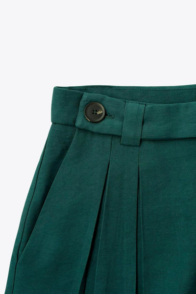 Pantalón fluido de fit wide leg, cintura alta con pretina, trabillas, pinzas frontales y bolsillos delanteros. Cierre frontal con cremallera oculta y detalle de botón lateral en pretina.