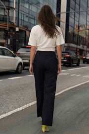 Pantalón de fit recto, cintura media con pretina ancha y trabillas, bolsillos delanteros y vivos decorativos posteriores. Cierre frontal con botones y cremallera oculta.