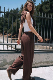 Pantalón de fit balloon, estampado rayas, pinzas frontales, cintura alta con pretina cruzada y trabillas, bolsillos delanteros, vivo decorativo posterior, cierre frontal con botón y cremallera oculta.