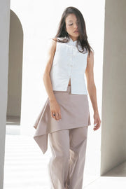 Pantalón recto de cintura alta con pretina, detalle de sobrefalda cruzada decorativa con bajo asimétrico, trabilla lateral, vivo decorativo posterior, cierre frontal con broche y cremallera ocultos.