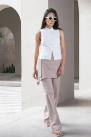 Pantalón recto de cintura alta con pretina, detalle de sobrefalda cruzada decorativa con bajo asimétrico, trabilla lateral, vivo decorativo posterior, cierre frontal con broche y cremallera ocultos.