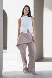 Pantalón recto de cintura alta con pretina, detalle de sobrefalda cruzada decorativa con bajo asimétrico, trabilla lateral, vivo decorativo posterior, cierre frontal con broche y cremallera ocultos.