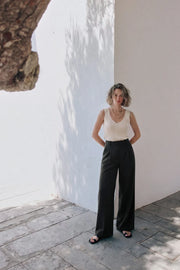 Pantalón de fit recto, pinzas frontales, cintura alta con pretina y trabillas, bolsillos delanteros, cierre frontal con broche y cremallera ocultos.