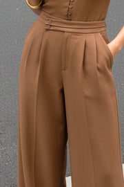 Pantalón de fit wide leg, cintura alta con pretina criss cross y detalle decorativo, pinzas frontales, bolsillos delanteros, cierre frontal con botones y cremallera oculta.
