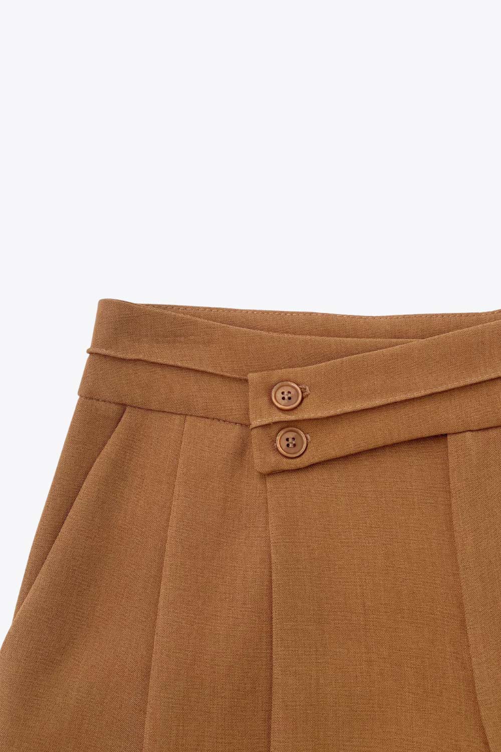 Pantalón de fit wide leg, cintura alta con pretina criss cross y detalle decorativo, pinzas frontales, bolsillos delanteros, cierre frontal con botones y cremallera oculta.