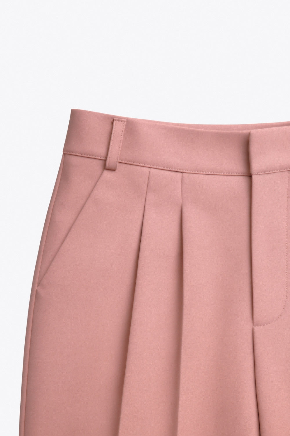 Pantalón de fit fluido, cintura alta con pretina y trabillas, pinzas frontales, bolsillos delanteros y vivo decorativo posterior. Cierre frontal con broche y cremallera ocultos.