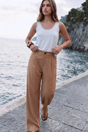 Pantalón de fit wide leg, cintura alta con pretina y trabillas, pinzas frontales, bolsillos delanteros y vivos decorativos posteriores. Cierre frontal con botón y cremallera oculta.