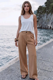 Pantalón de fit wide leg, cintura alta con pretina y trabillas, pinzas frontales, bolsillos delanteros y vivos decorativos posteriores. Cierre frontal con botón y cremallera oculta.