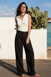 Pantalón de fit wide leg, cintura alta con pretina elástica posterior y trabillas, pinzas frontales, bolsillos delanteros y vivo decorativo posterior. Cierre frontal con broche y cremallera ocultos. Detalle de raya frontal y posterior.