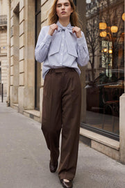 Pantalón de fit wide leg, cintura alta con pretina elástica posterior y trabillas, pinzas frontales, bolsillos delanteros y vivo decorativo posterior. Cierre frontal con broche y cremallera ocultos. Detalle de raya frontal y posterior.