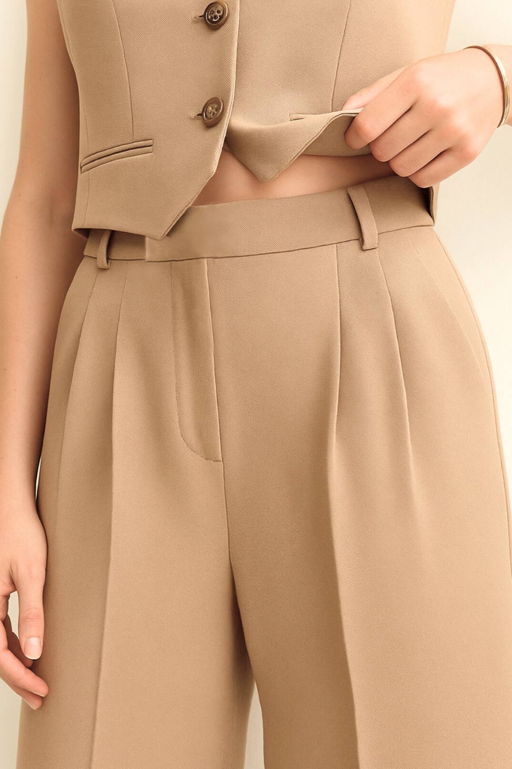 Pantalón de fit wide leg, cintura alta con pretina elástica posterior y trabillas, pinzas frontales, bolsillos delanteros y vivo decorativo posterior. Cierre frontal con broche y cremallera ocultos. Detalle de raya frontal y posterior.