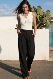 Pantalón de fit wide leg, cintura alta con pretina elástica posterior y trabillas, pinzas frontales, bolsillos delanteros y vivo decorativo posterior. Cierre frontal con broche y cremallera ocultos. Detalle de raya frontal y posterior.