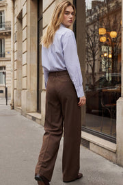 Pantalón de fit wide leg, cintura alta con pretina elástica posterior y trabillas, pinzas frontales, bolsillos delanteros y vivo decorativo posterior. Cierre frontal con broche y cremallera ocultos. Detalle de raya frontal y posterior.