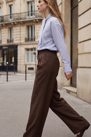 Pantalón de fit wide leg, cintura alta con pretina elástica posterior y trabillas, pinzas frontales, bolsillos delanteros y vivo decorativo posterior. Cierre frontal con broche y cremallera ocultos. Detalle de raya frontal y posterior.