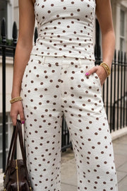 Pantalón de fit recto, estampado polka dot, cintura alta con pretina elástica posterior y trabillas, bolsillos delanteros, cierre frontal con broche y cremallera oculta.