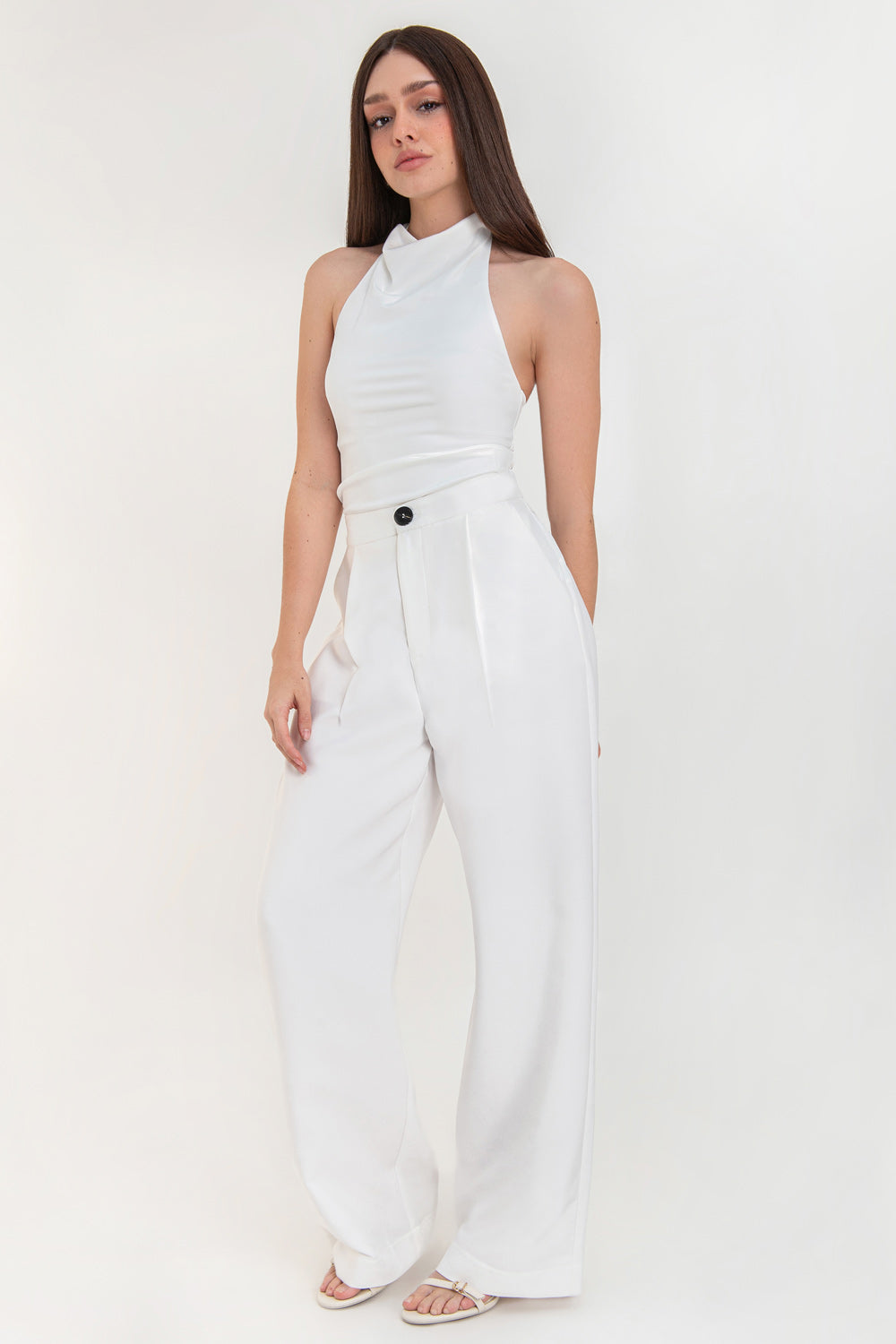 Pantalón de fit wide leg, pinzas frontales, bolsillos delanteros, cintura alta con pretina elástica posterior, cierre frontal con cremallera oculta y botón en contraste.