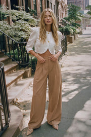Pantalón de fit wide leg, cintura media con pretina, trabillas ajustables laterales, pinzas frontales, bolsillos delanteros y vivos decorativos posteriores. Cierre frontal con broche y cremallera ocultos.